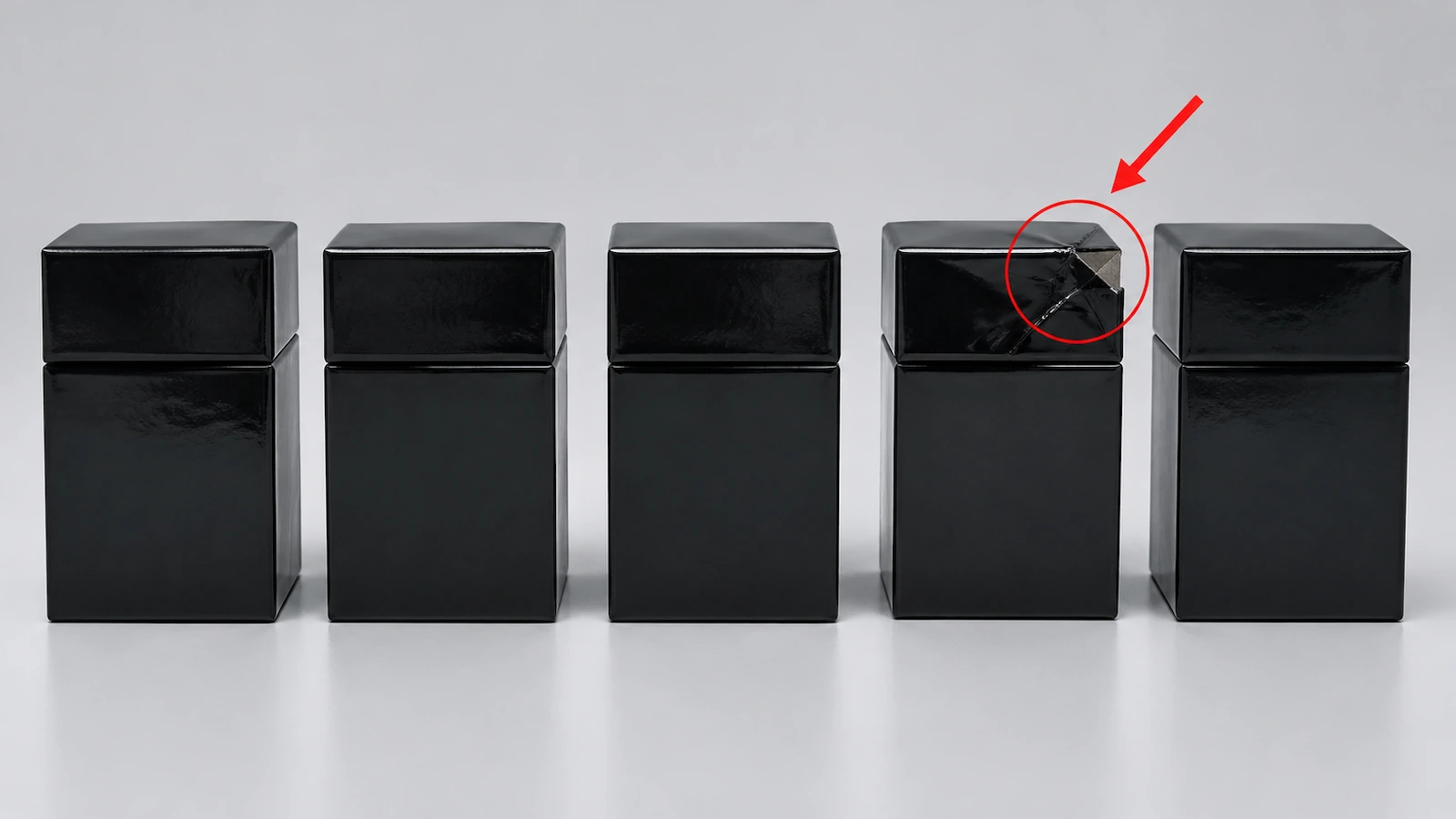 Rangée de boîtes rigides noires identiques en 2 pièces, dont l'une a un coin écrasé signalé par un cercle rouge et une flèche diagonale rouge