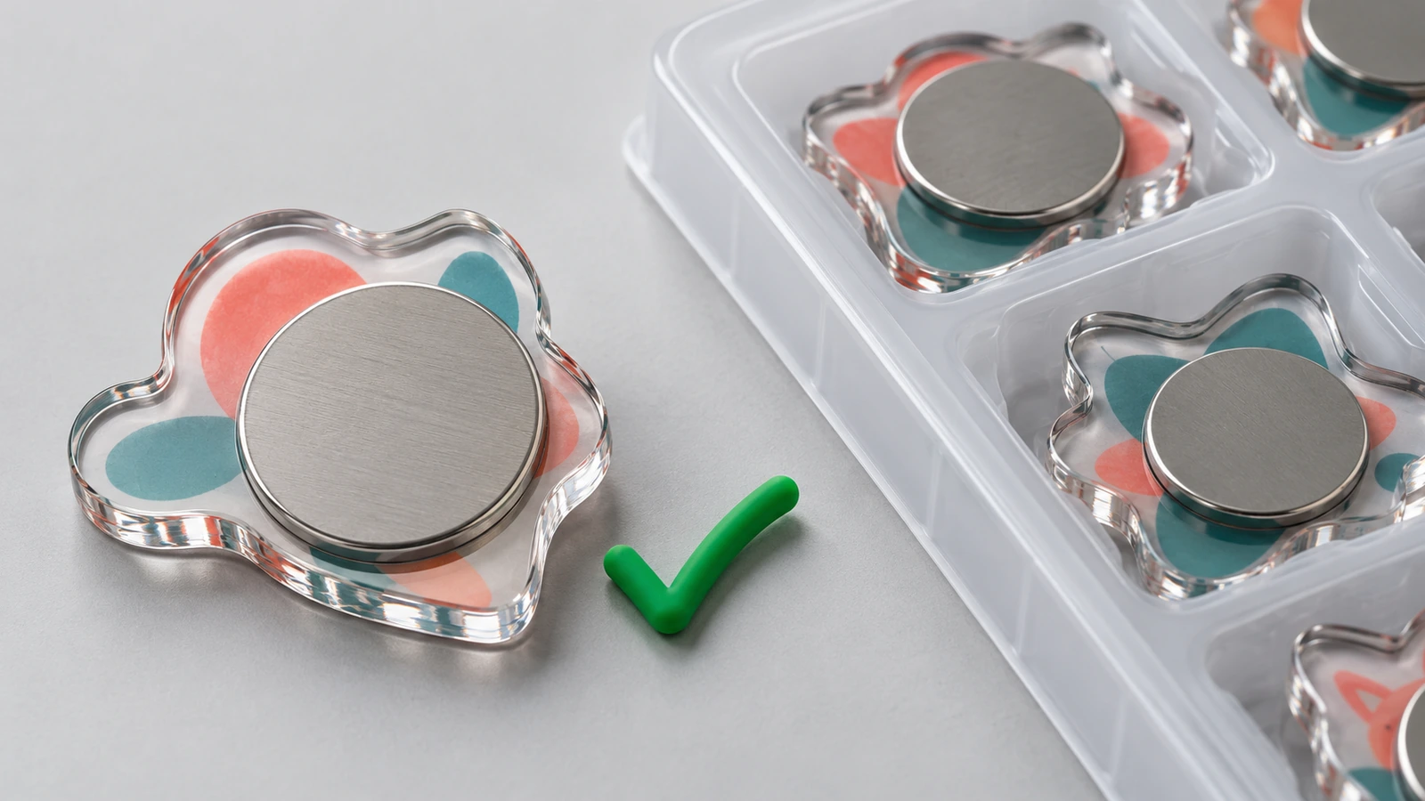 Gros plan sur le dos d'un magnet en acrylique transparent, montrant un disque magnétique entièrement collé à fleur de la surface, à côté d'un plateau de protection