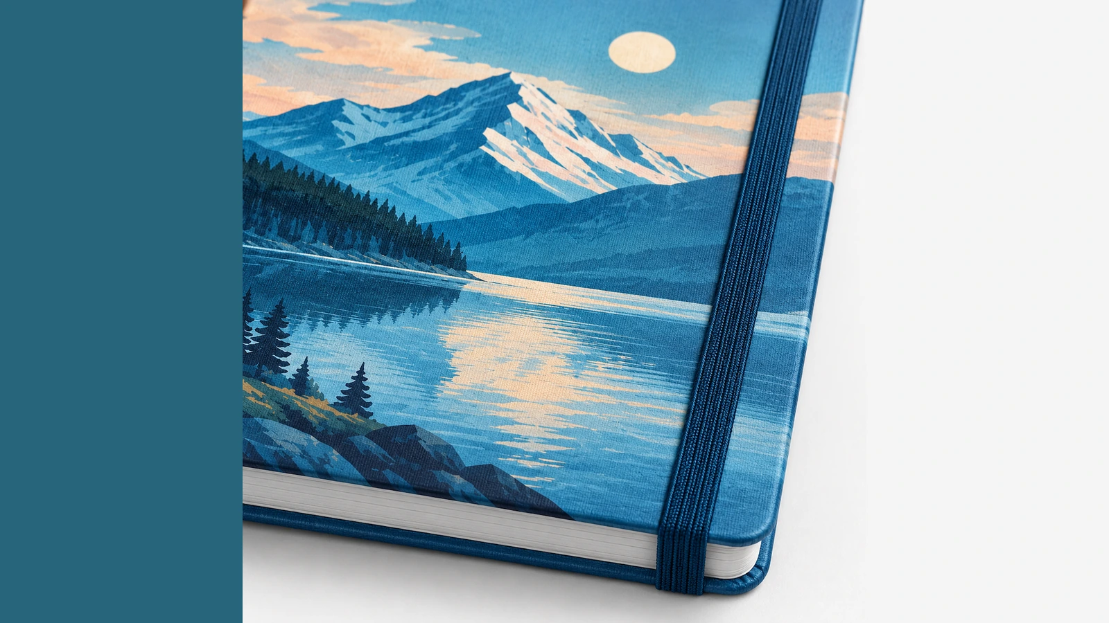 Gros plan illustratif d'une couverture imprimée au motif lac de montagne, d'un élastique bleu et du bloc de pages
