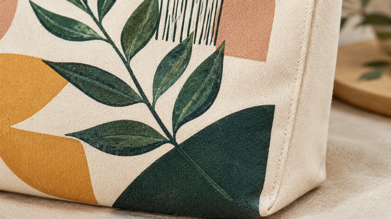 Gros plan d'un tote bag en toile imprimé montrant le motif de feuilles et un soufflet latéral cousu