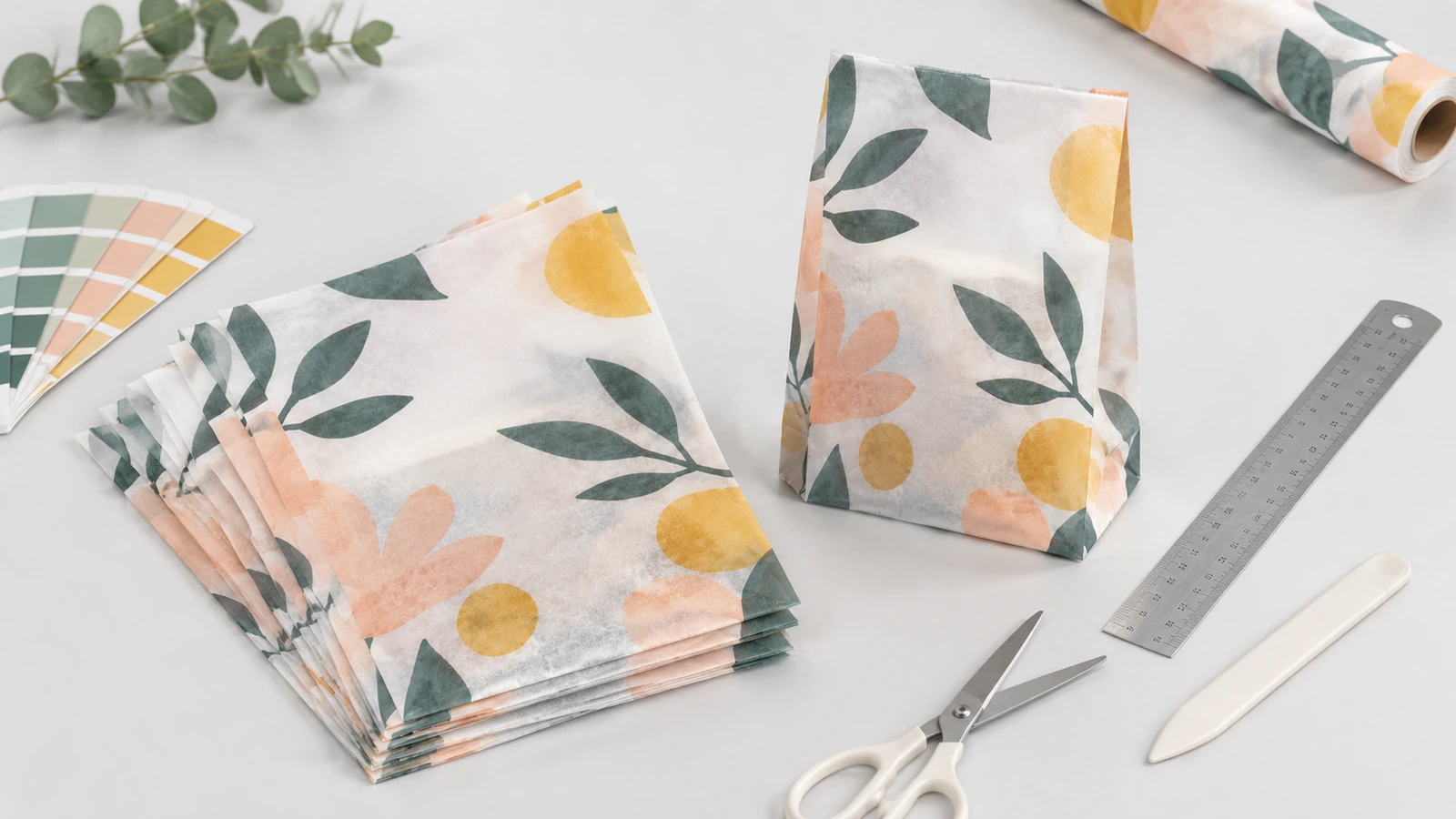 Sacs en papier translucide imprimés de motifs floraux, avec un rouleau de papier, une règle, des ciseaux et des nuanciers
