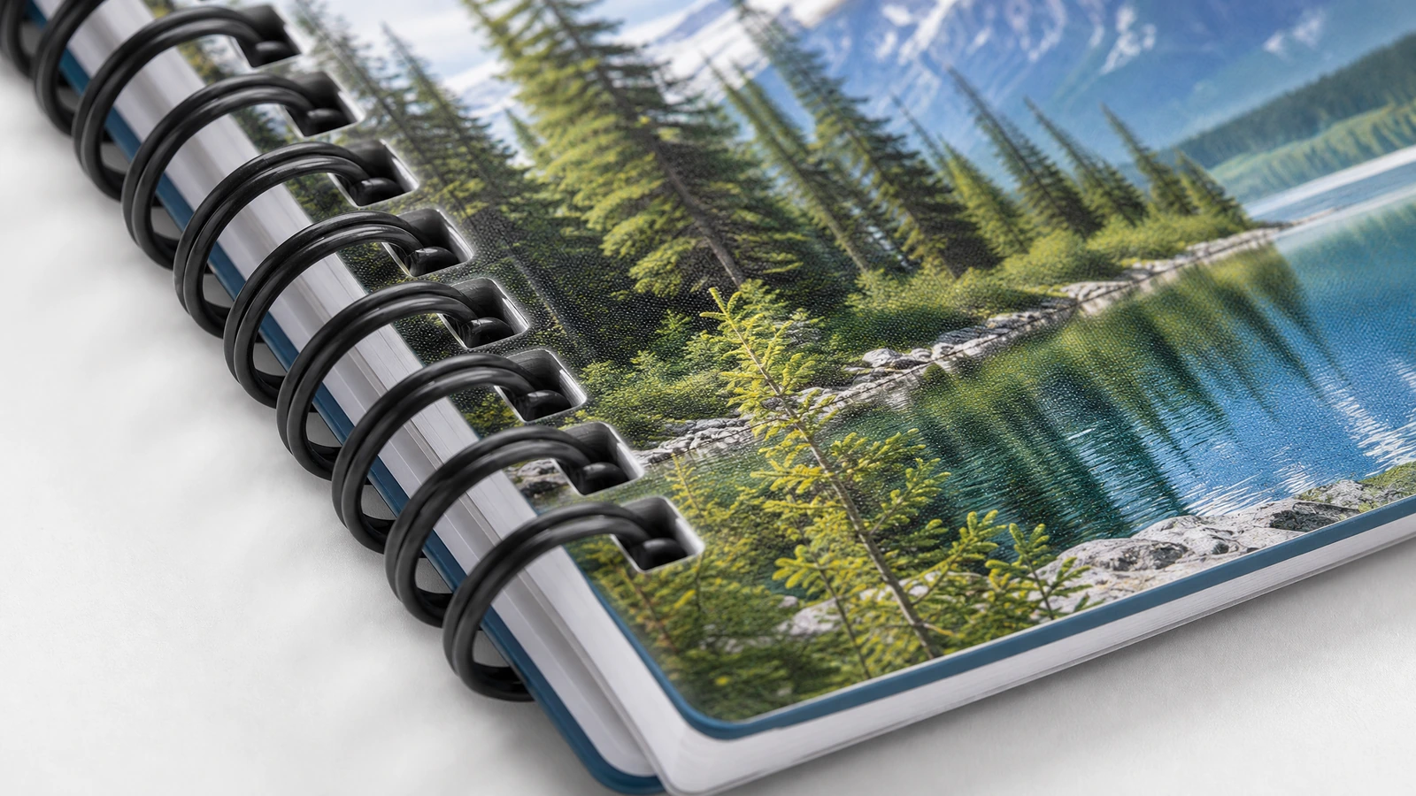 Gros plan illustratif sur la reliure d’un carnet noir et sur une couverture imprimée représentant un lac de montagne