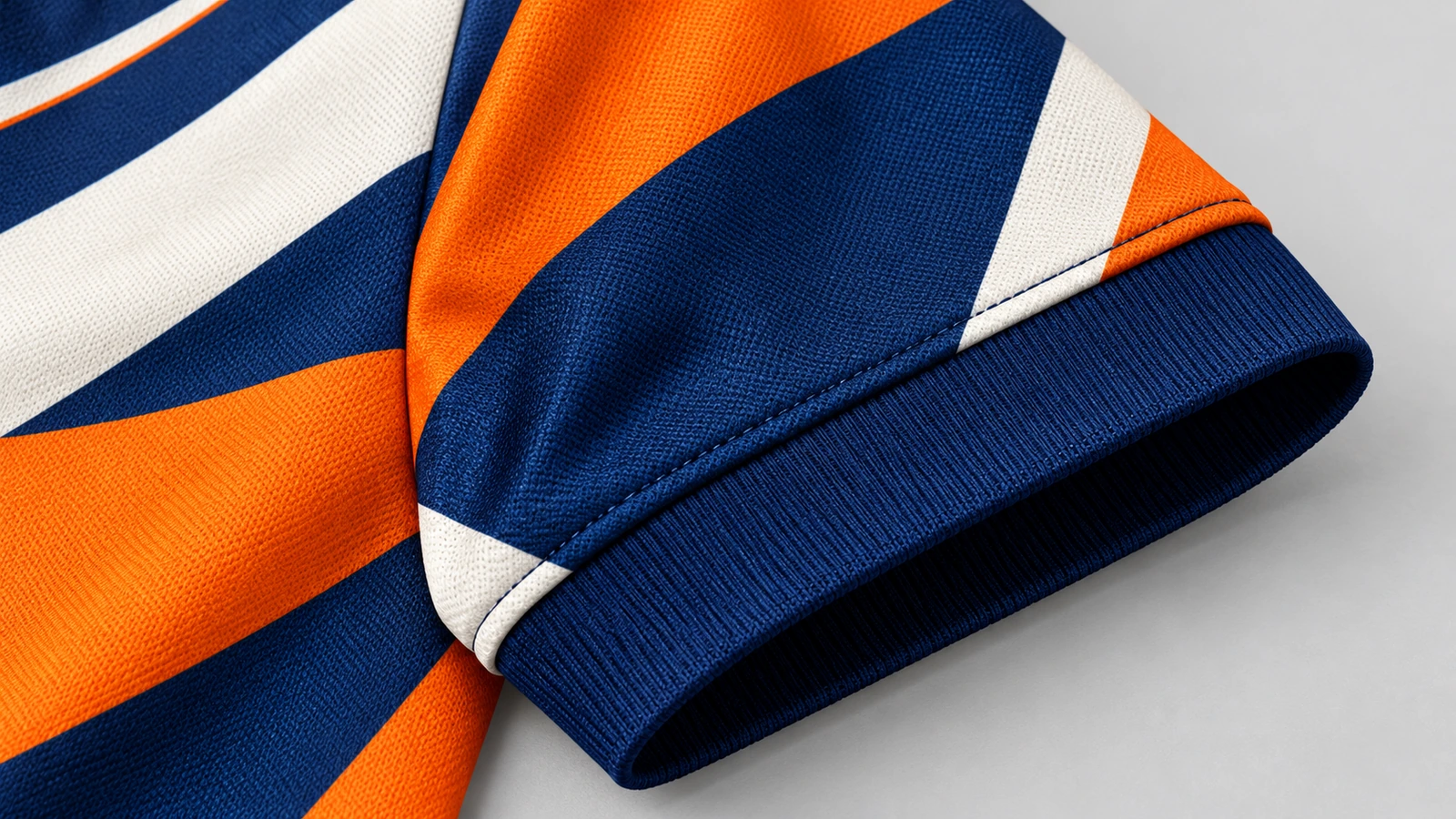 Gros plan sur une manche à motifs orange, bleu marine et blanc avec un poignet en côte bleu marine